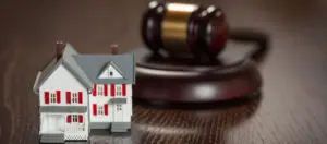 A small toy house sitting in front of a gavel.