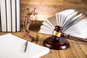A law book, gavel and statue of justice on top of a table.